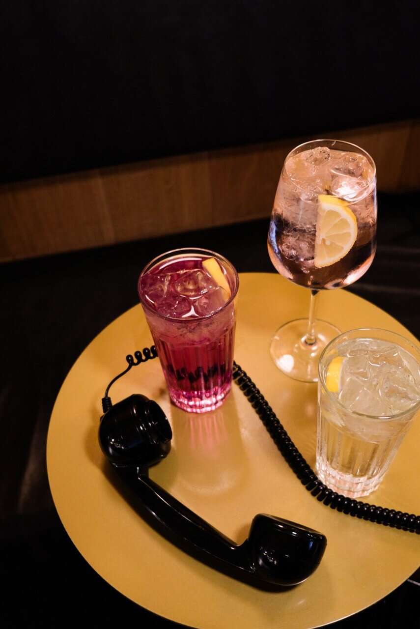 Image that portrays 'the weekend is calling'. Three different gin tonics with a phone next to it.