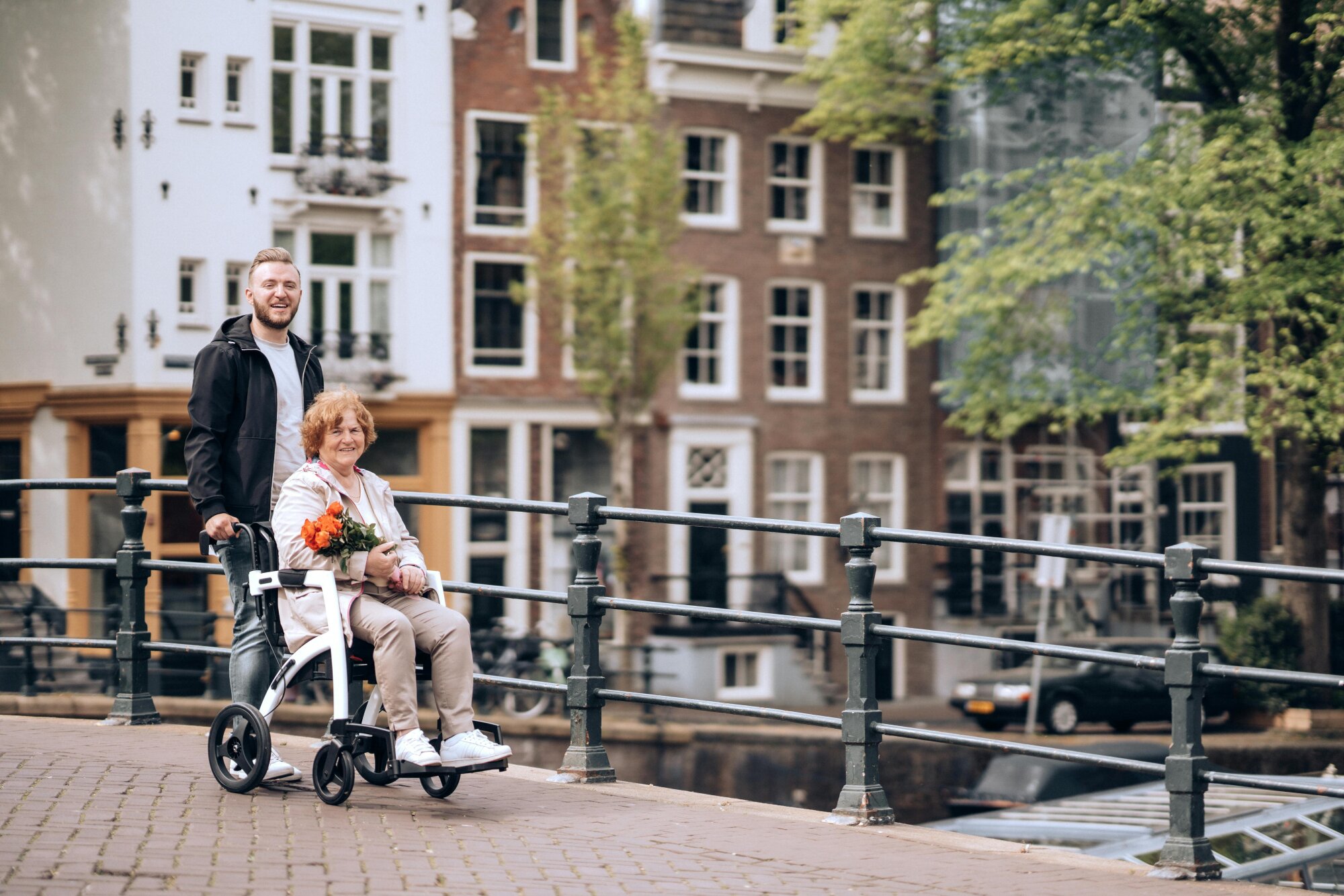 Woman in a wheelchair being pushed through Amsterdam. Read this blog for wheelchair friendly activities in Amsterdam.