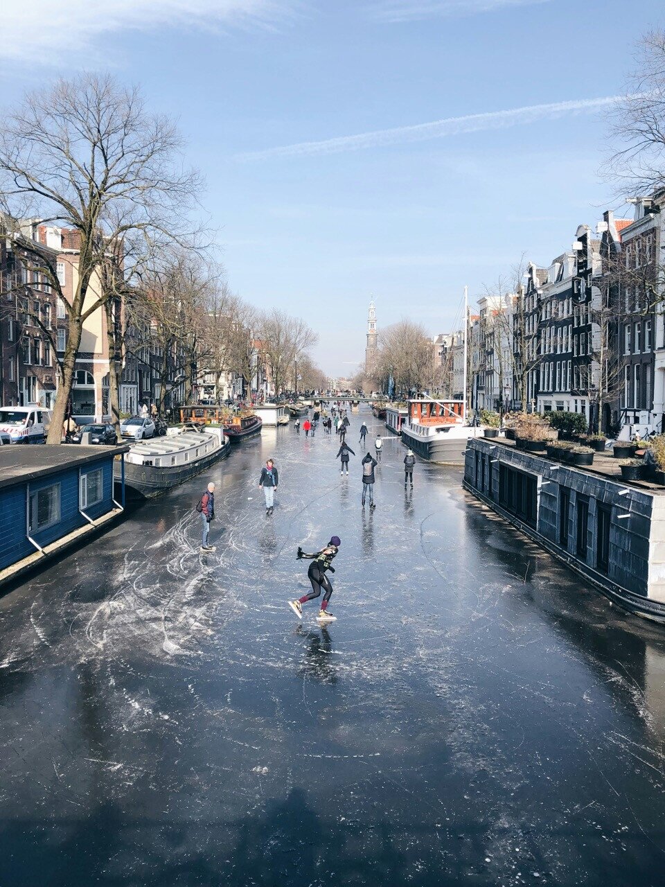 Winter in Amsterdam. People ice skating on the canals on a sunny winter day in amsterdam.